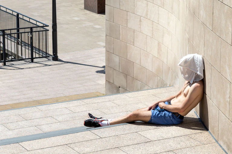 Topless man with a T-shirt over his head during London heatwave in Canary Wharf, London.