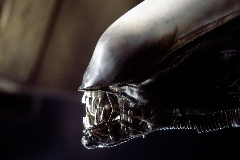 A silvery grey alien-like creature with enormous silvery teeth.