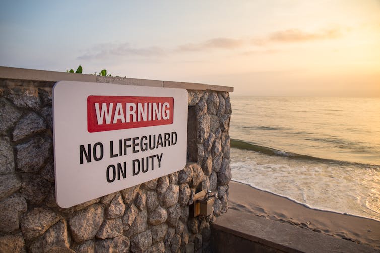 A sign at a beach warning there is no lifeguard on duty.