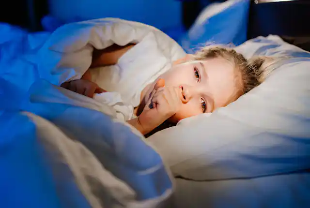Girl coughs while laying in bed