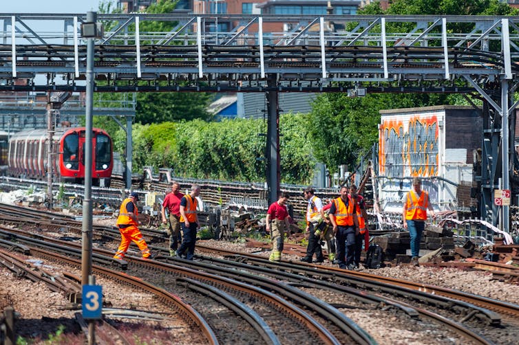 Rail maintenance workers assessing track damage during a heatwave.