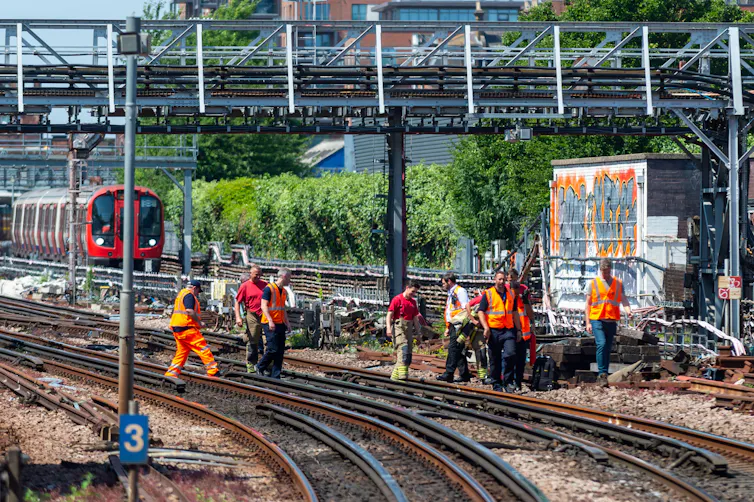 Rail maintenance workers assessing track damage during a heatwave.