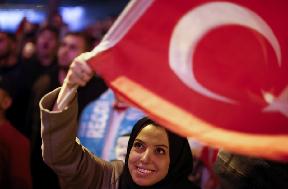 A woman in a headscarf waves a Turkish flag.
