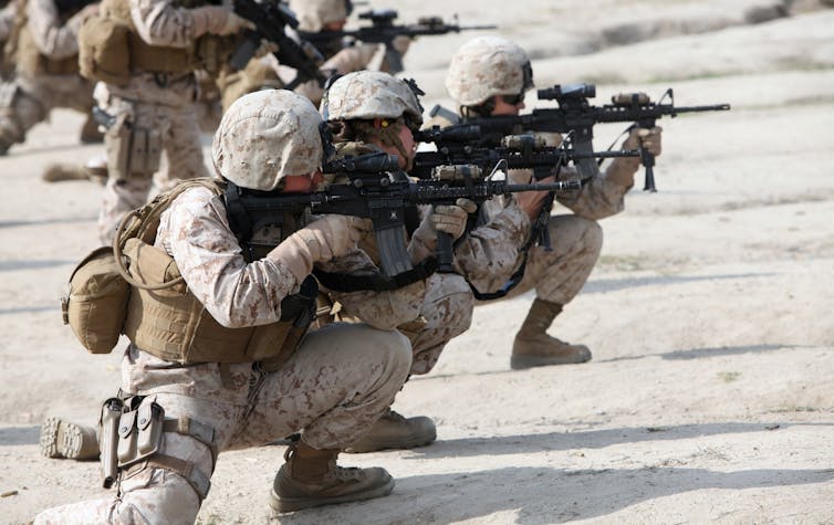 US female marines crouching with their weapons
