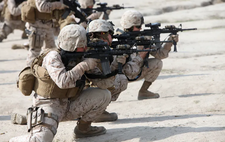 US female marines crouching with their weapons