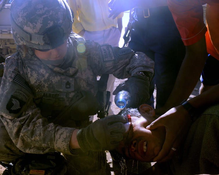 A female soldier cleans the wound of a child