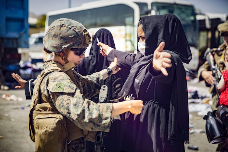 A US marine conducts an inspection of an Afghan woman