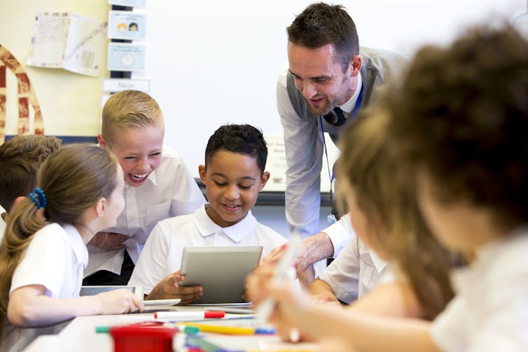A teacher works with young students on a reading task.