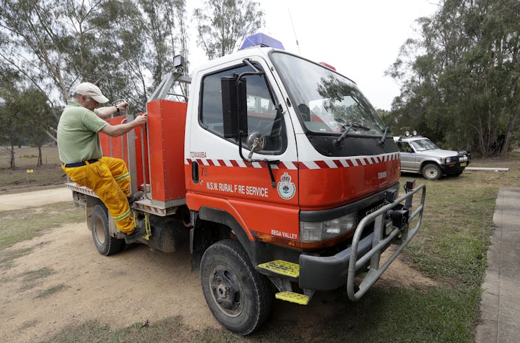 A volunteer climbs up onto a NSW Rural Fire Service truck