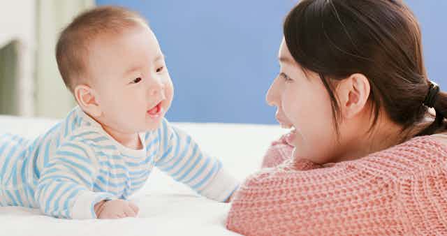 Mother talking to baby on bed