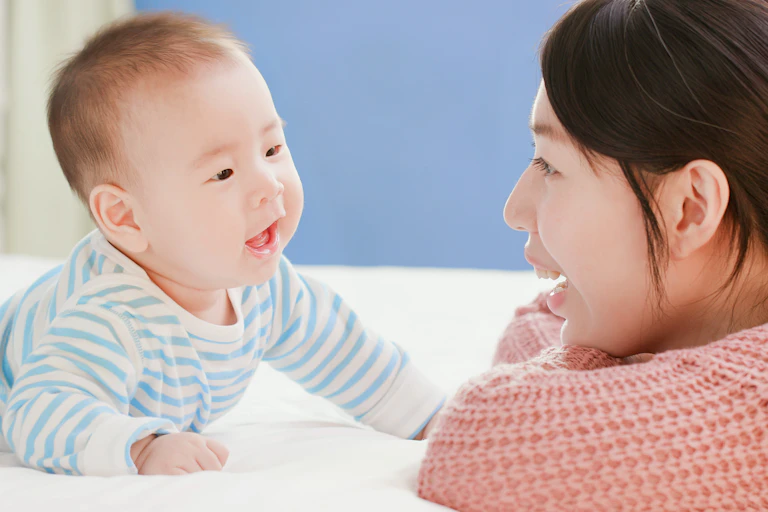 Mother talking to baby on bed