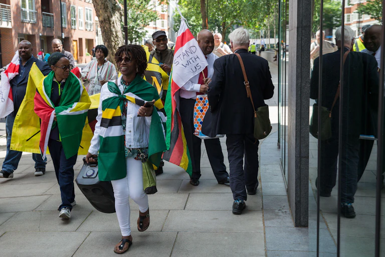 Protestors with flags pass a blonde man in the street.