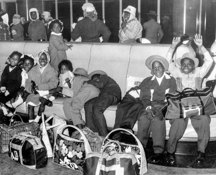 An archival photograph in black and white of children seated on benches.
