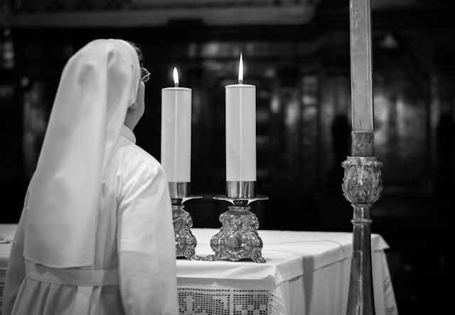 A nun blows out church candels.