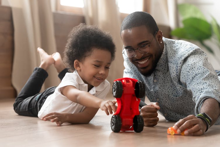 Father and young son play together with toy cars