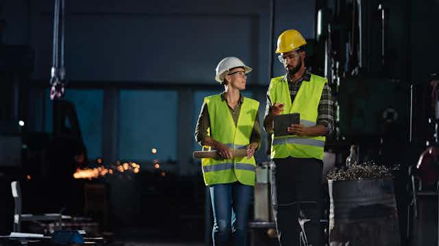 A female and male industrial worker at night.