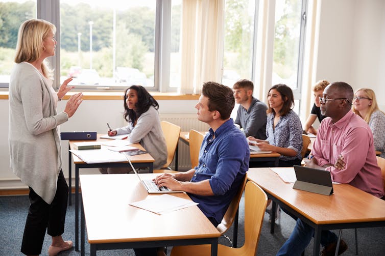 A woman standing in front of people seated in a classroom.