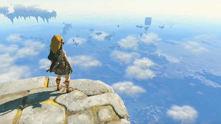 Video game character stood on a ledge looking through clouds at a world below.