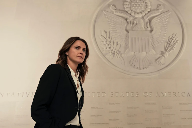 Una mujer con traje delante del escudo de Estados Unidos de América.