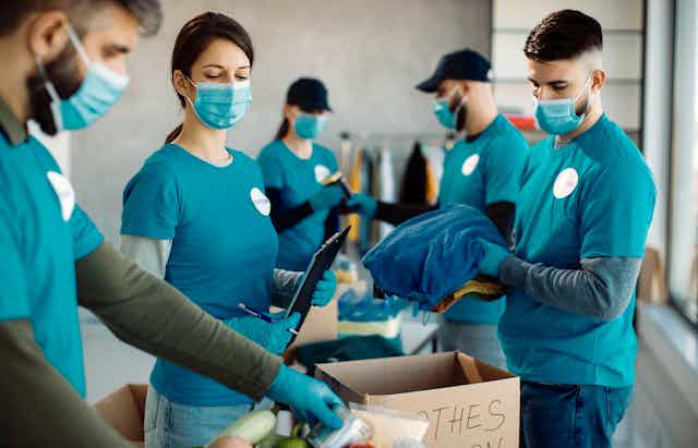Volunteers placing donated clothes in a box.