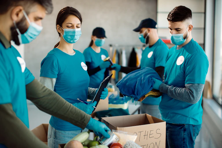 Volunteers placing donated clothes in a box.