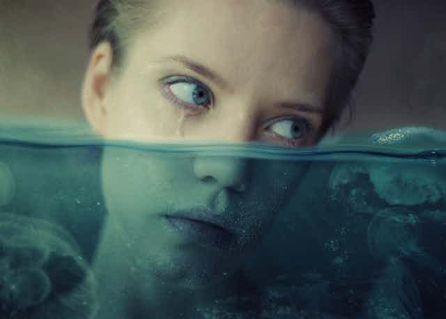 The bottom half of a woman's head is tilted underwater as she looks off to the side 