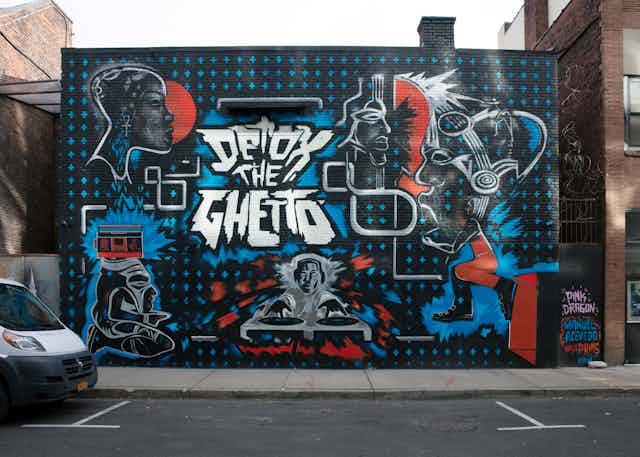 A spray-painted mural on the side of a building features the phrase "Detox the Ghetto"