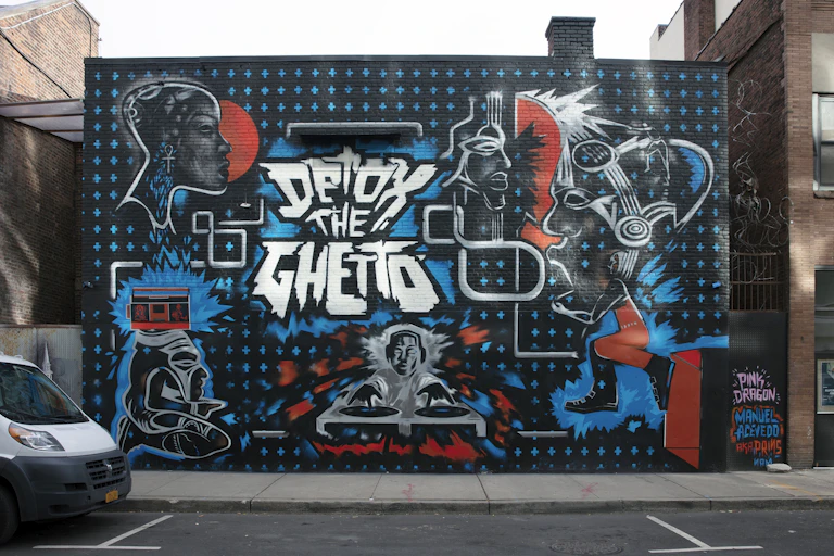 A spray-painted mural on the side of a building features the phrase "Detox the Ghetto"