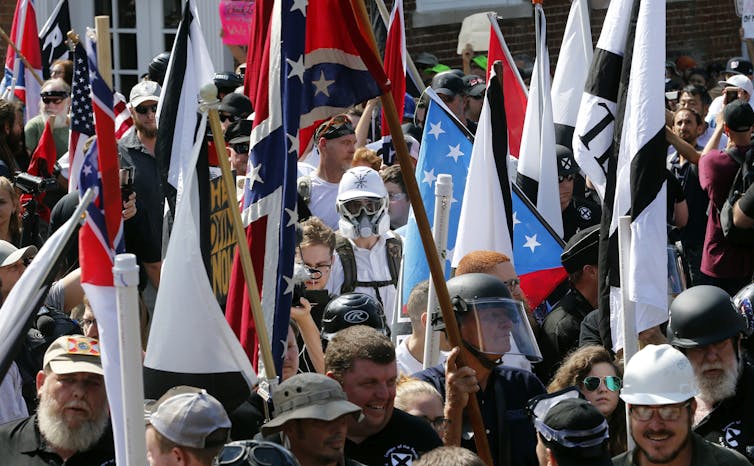 A ragtag group of white men, some in helmets, some carrying confederate flags