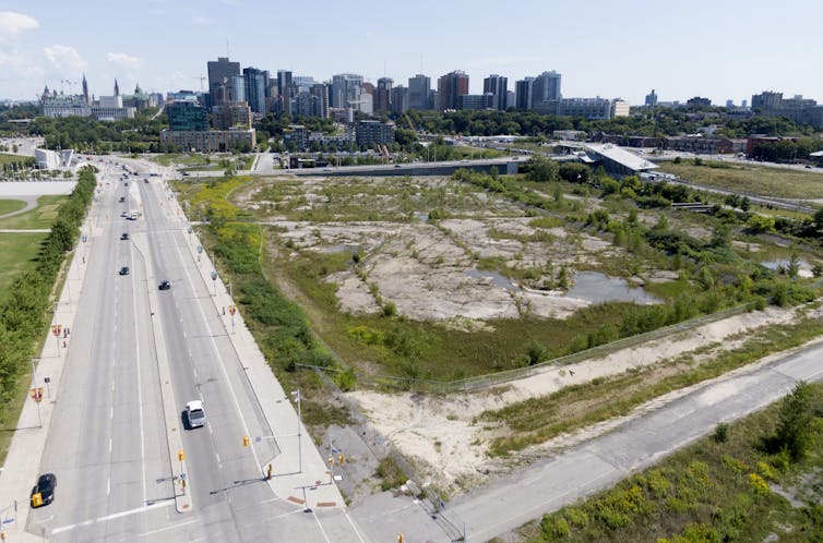 A large tract of undeveloped land with the skyline of a city in the background.