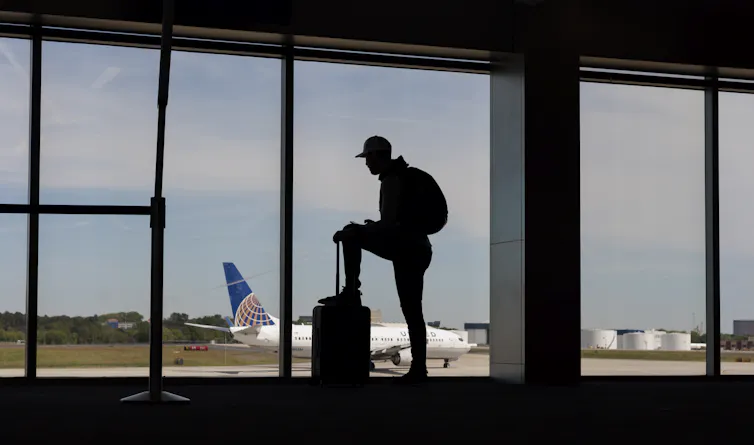 man with bag looks at plane
