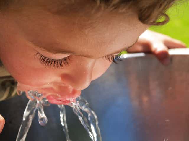 young child drinks from water fountain