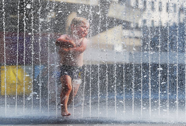 boy plays in fountain during heatwave