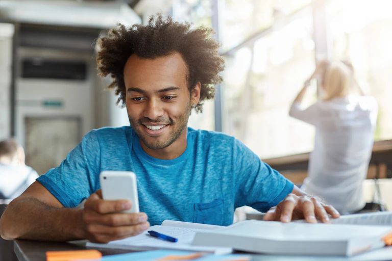 Young man smiles while looking at his phone.