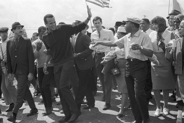 Harry y Belafonte waves to Dr. Martin Luther King, Jr. as he leaves civil rights marchers in Montgomery, Alabama in 1965.