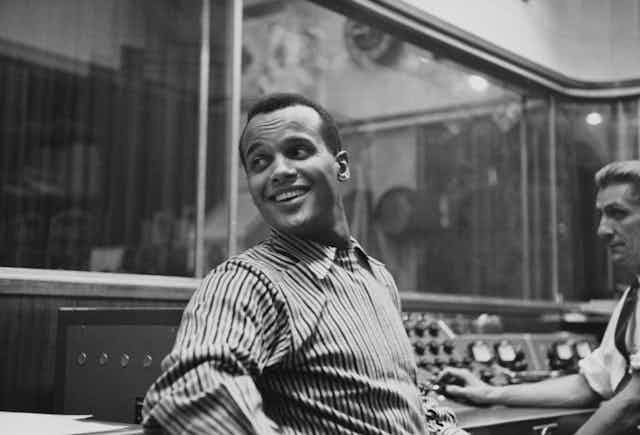 Harry Belafonte seated in a recording studio in the late 1950s.