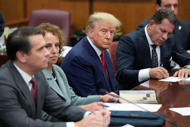 Donald Trump sits at a table with his legal team in a court room.
