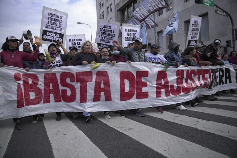a group of people marching with a sign reading BASTA DE AJUSTERIA