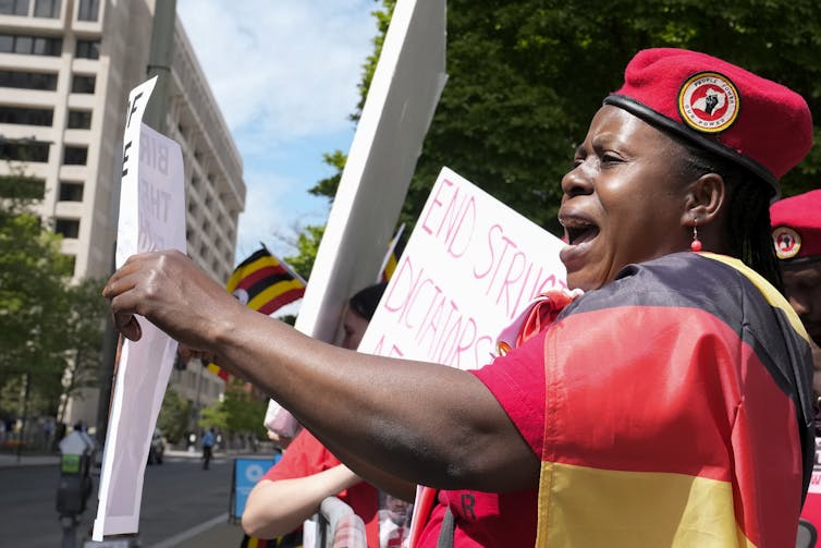 Una mujer vestida de negro, amarillo y rojo -los colores de la bandera de Uganda- grita en señal de protesta.
