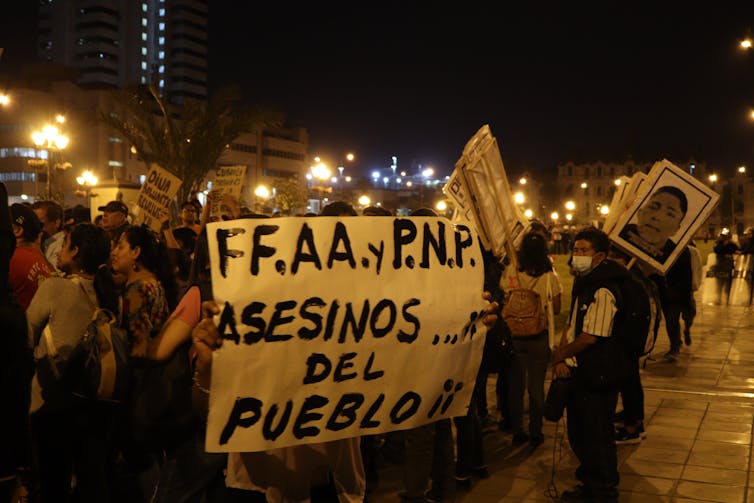 Des manifestants brandissent une bannière accusant les forces de l’ordre d’être les assassins du peuple