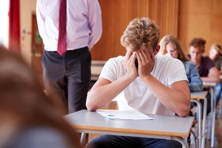 Student in exam hall with head in hands