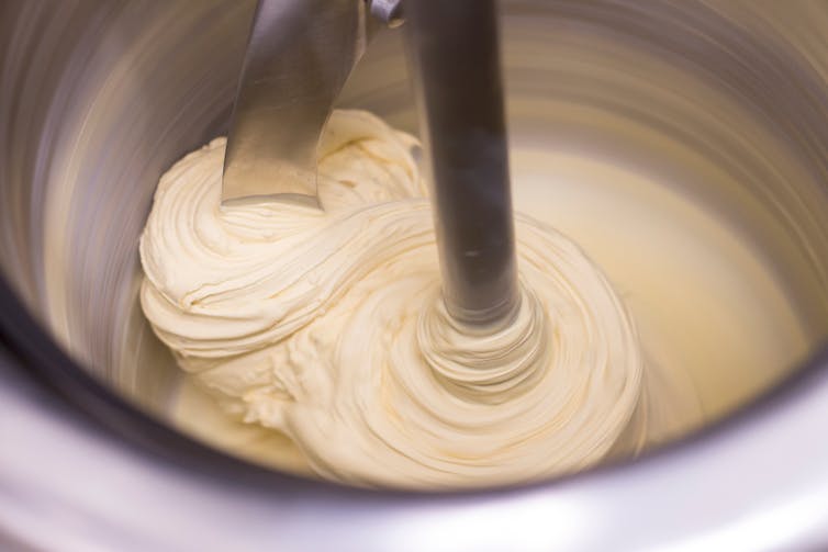 Close up of ivory coloured ice cream being churned in a stainless steel container