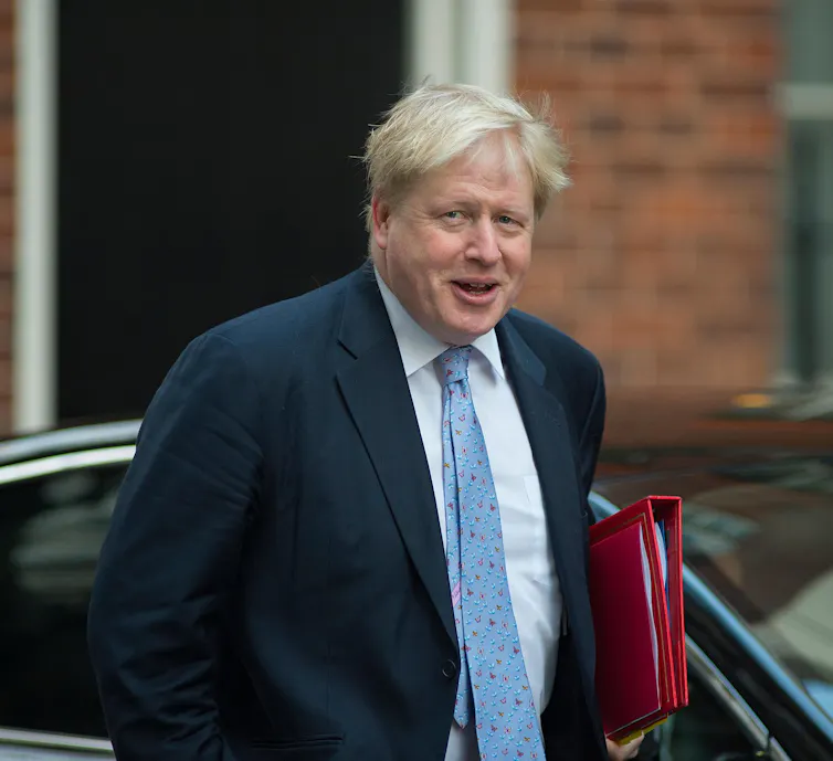 Boris Johnson carrying a red folder.