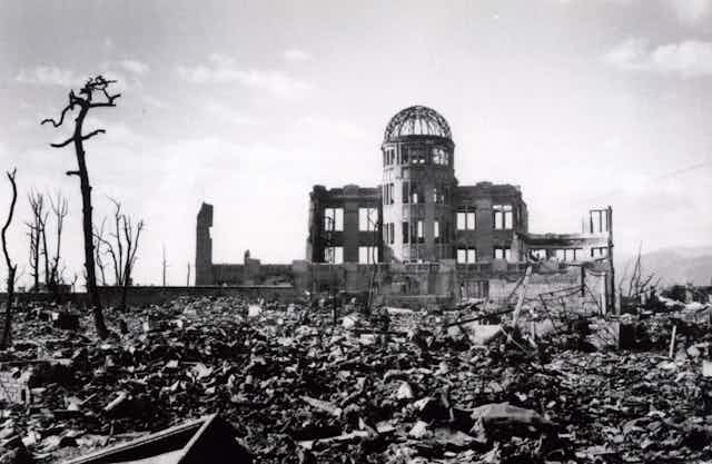 The flattened city of Hiroshima showing rubble and a bombed out building barely standing.