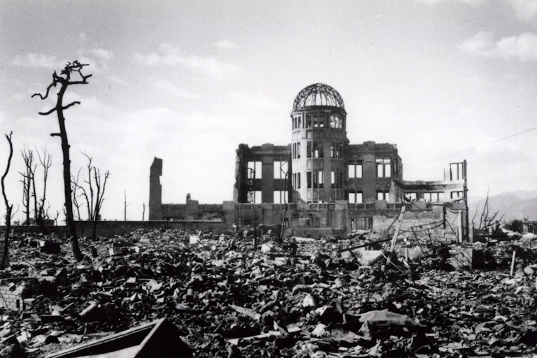 The flattened city of Hiroshima showing rubble and a bombed out building barely standing.
