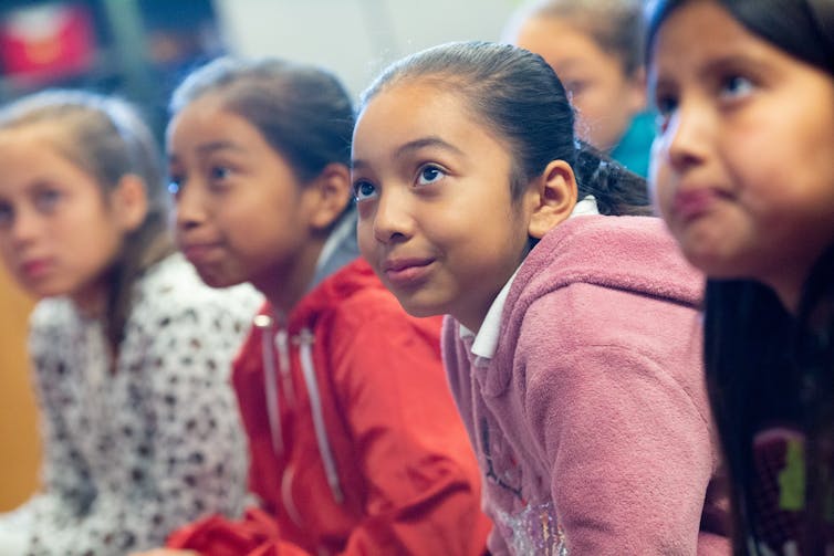 Students seen sitting in a classroom listening.