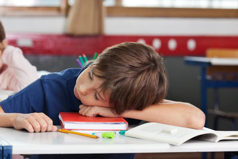 Students seen in a classroom, one with their head on a desk.