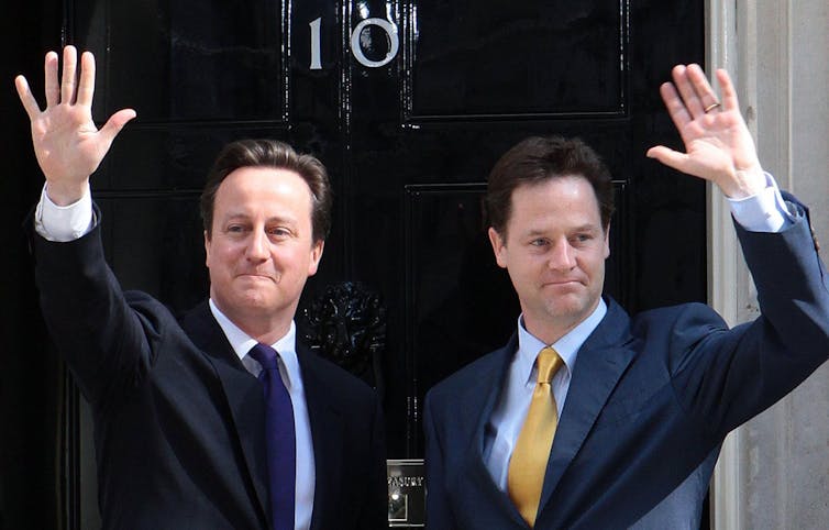 David Cameron and Nick Clegg waving outside 10 Downing Street.