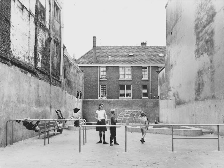 Children playing on a playground in a black and white photograph.