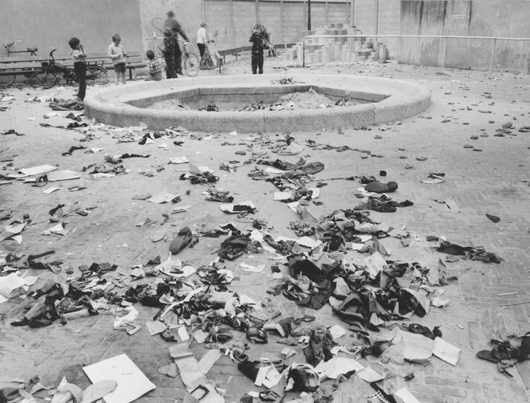 An archival photograph of a playground with children on bikes and rubbish.